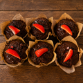 Box of six double chocolate muffins with chocolate drizzle and fresh strawberry garnish